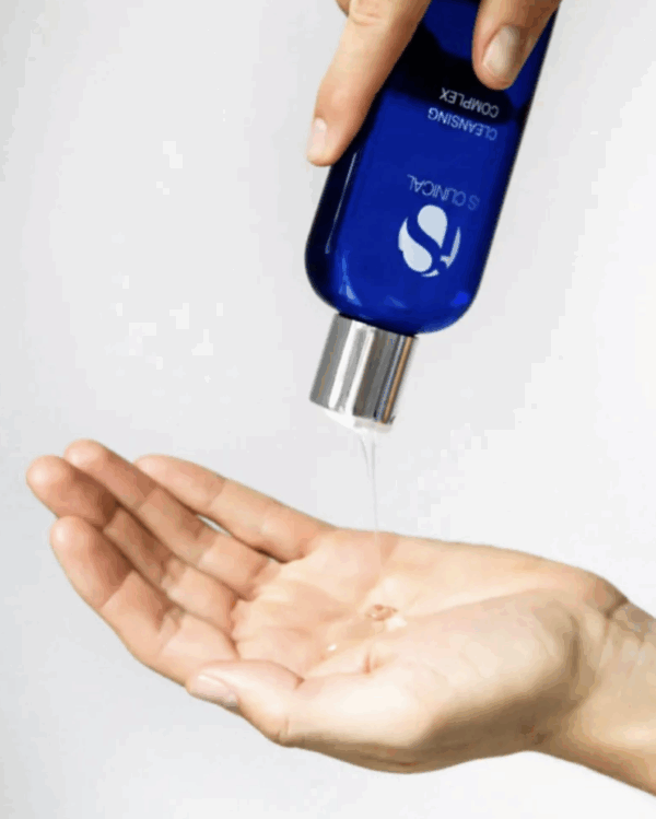A person pours a clear liquid cleanser from a blue bottle labeled "Is Clinical Pure Radiance Collection" into their hand, highlighting the product against a plain white background.